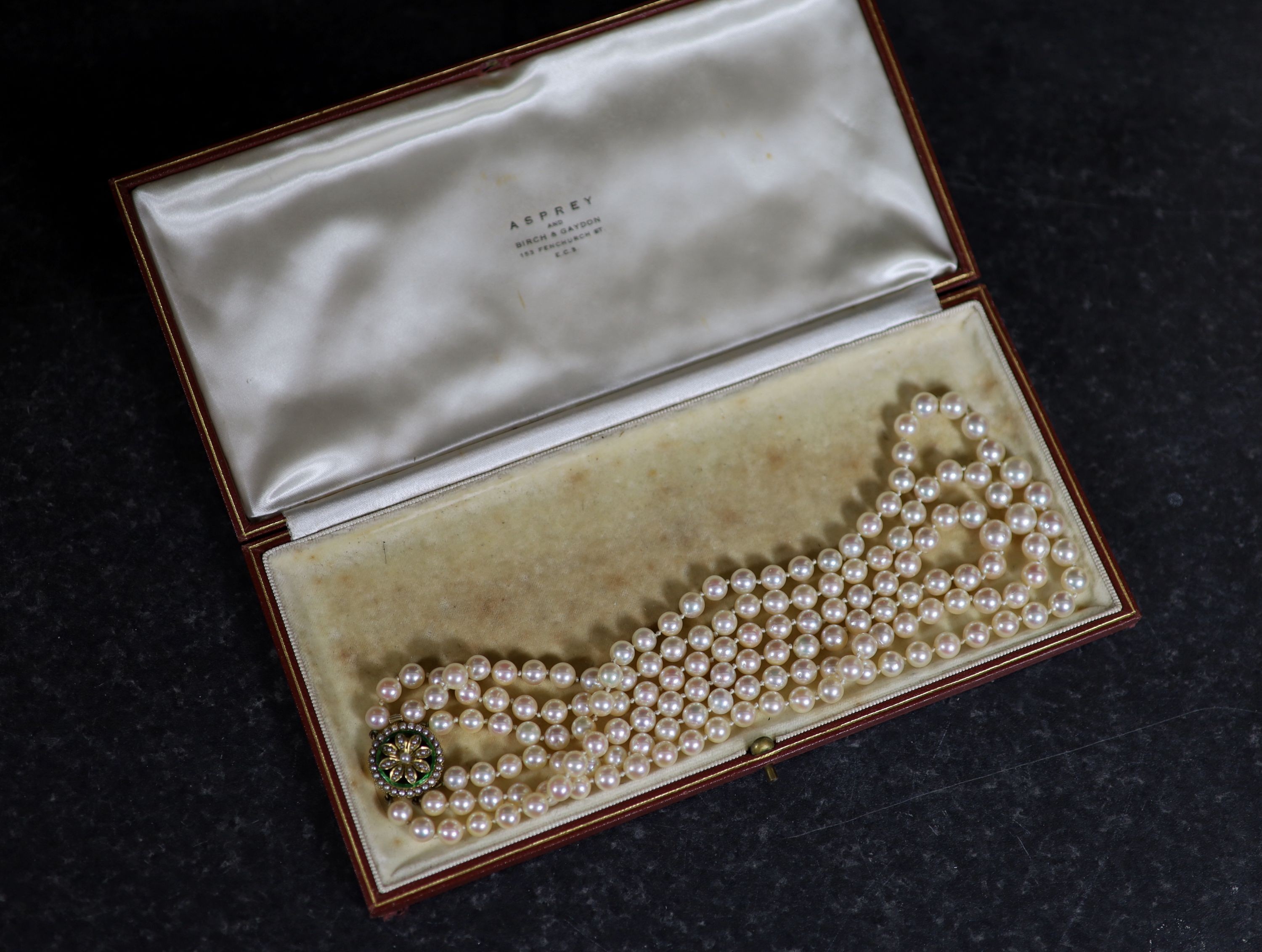 A mid 20th century triple strand cultured pearl choker necklace, with gold, seed pearl and enamel set circular clasp